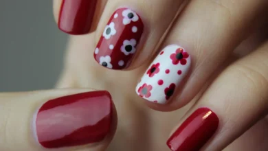 Unhas curtas com esmalte vermelho e decoração floral em branco e vermelho, mostrando estilo e delicadeza.
