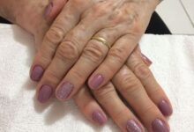 Unhas pintadas em tom lilás com detalhes em glitter nas mãos de mulher madura