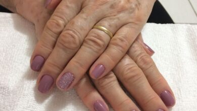 Unhas pintadas em tom lilás com detalhes em glitter nas mãos de mulher madura