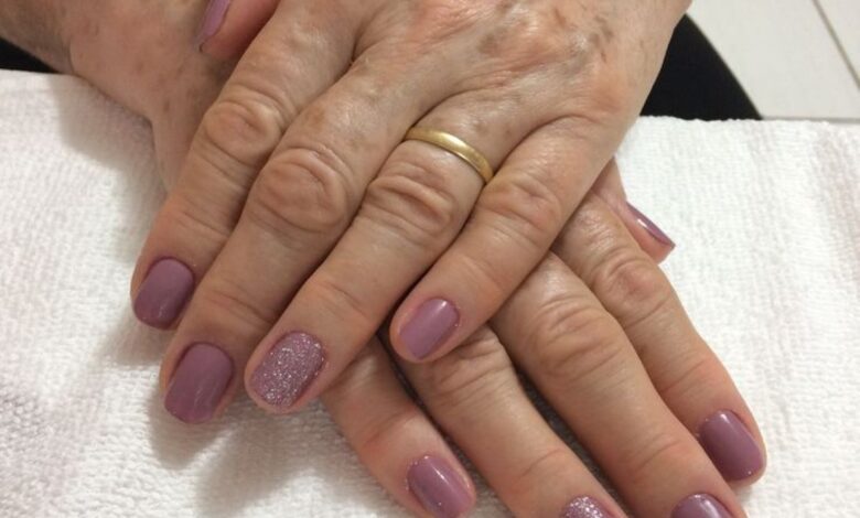 Unhas pintadas em tom lilás com detalhes em glitter nas mãos de mulher madura