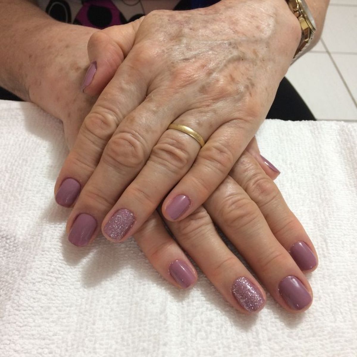 Unhas pintadas em tom lilás com detalhes em glitter nas mãos de mulher madura