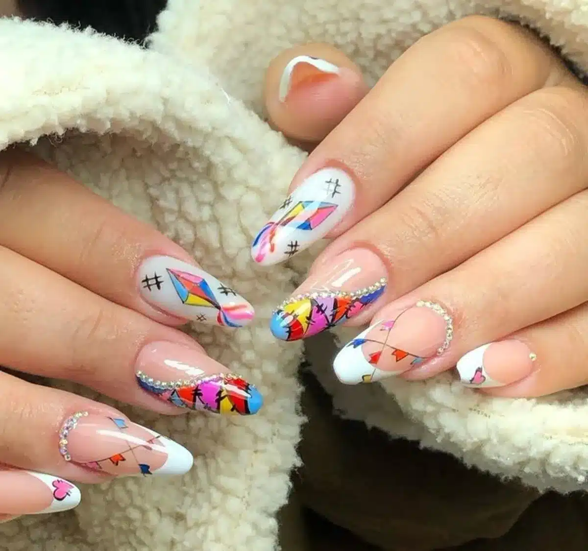 Unhas decoradas com bandeirinhas coloridas, balões e detalhes brilhantes para a Festa Junina.