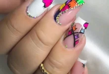 Unhas decoradas coloridas e modernas com pedras brilhantes, design vibrante e detalhes geométricos.