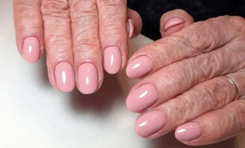 Unhas cuidadas e elegantes em mãos maduras com esmalte rosado