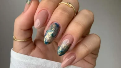 Unhas redondas decoradas com esmalte nude e detalhes em azul e dourado