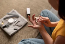 Pessoa fazendo cuidados nas unhas em casa, aplicando produto na mão