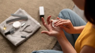 Pessoa fazendo cuidados nas unhas em casa, aplicando produto na mão