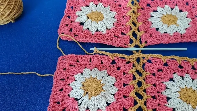 União de quadrados de crochê com ponto em bege formando uma linha entre eles, mostrando detalhe do trabalho manual