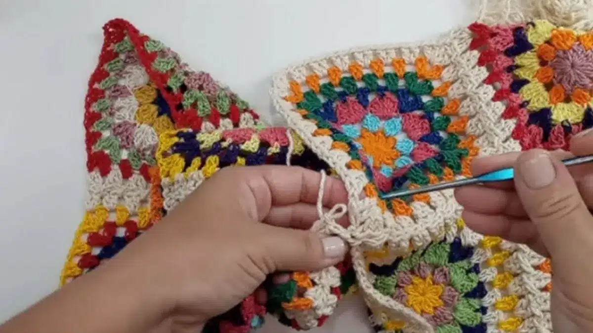 Detalhe da união de quadradinhos de crochê com agulha, técnica sem costura aparente
