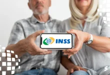 Casal de idosos segurando um celular com o logo do INSS, simbolizando a consulta de valores a receber.