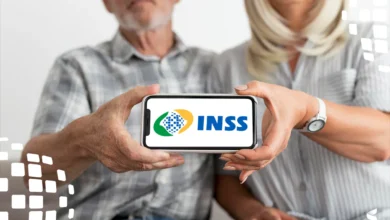 Casal de idosos segurando um celular com o logo do INSS, simbolizando a consulta de valores a receber.