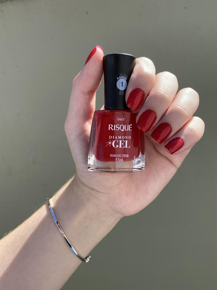 Esmalte vermelho da Risqué Diamond Gel, cor Vermelho Cereja, com aplicação nas unhas e brilho.