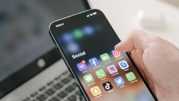 Imagem de um smartphone com aplicativos de redes sociais, incluindo o WhatsApp, em destaque na tela inicial