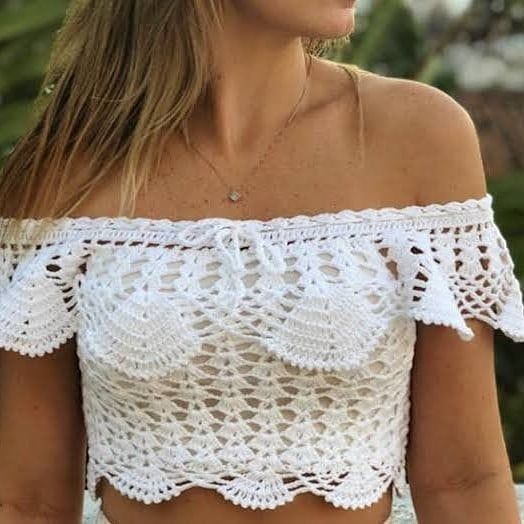 Mulher usando blusa ciganinha de crochê branca com detalhes delicados