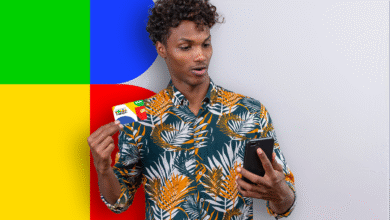 Homem surpreso segura cartão do Bolsa Família enquanto olha o celular.