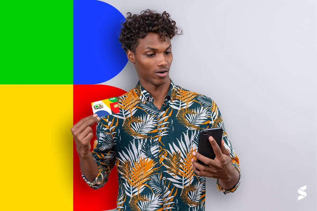 Homem segurando um cartão do programa Bolsa Família e smartphone, olhando surpreso para a tela, simbolizando a importância do auxílio.