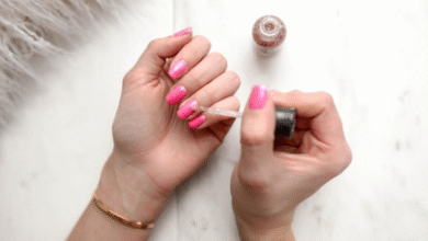 Pessoa aplicando esmalte cintilante em unhas pintadas de rosa