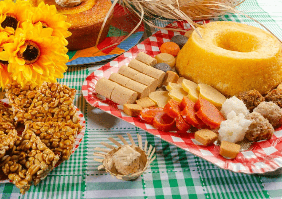 Comidas típicas de festa junina, com doces, bolo e outros quitutes tradicionais.