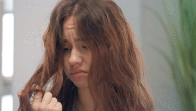 Mulher com cabelo ondulado e frizz, demonstrando insatisfação com os fios arrepiados.