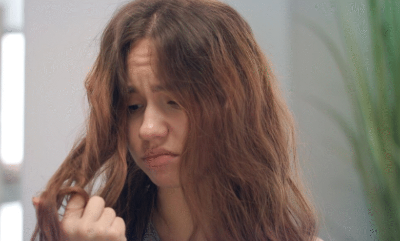 Mulher com cabelo ondulado e frizz, demonstrando insatisfação com os fios arrepiados.