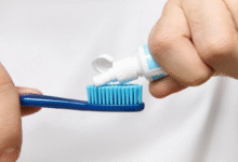 Pessoa aplicando creme dental em uma escova de dentes azul