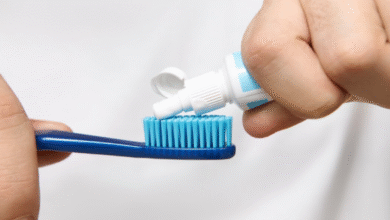 Pessoa aplicando creme dental em uma escova de dentes azul