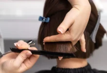 Profissional cortando cabelo de uma cliente, com foco no corte de um pixie com franja lateral em salão de beleza.