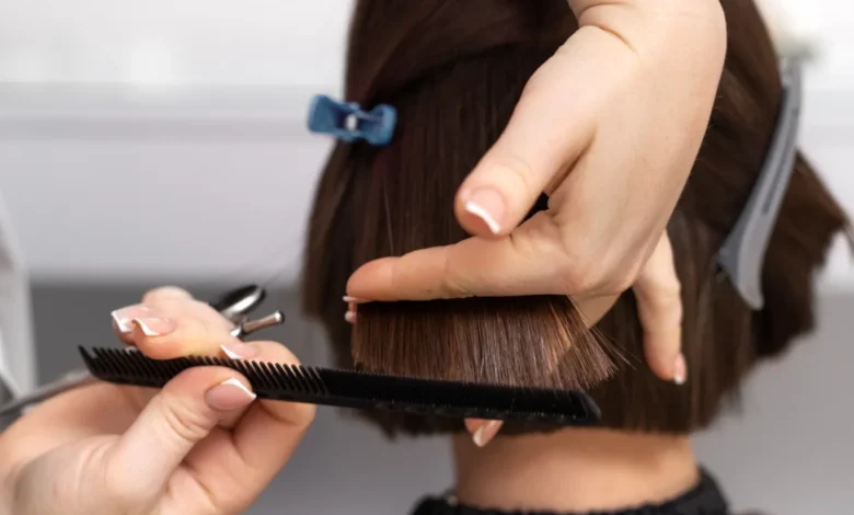 Profissional cortando cabelo de uma cliente, com foco no corte de um pixie com franja lateral em salão de beleza.