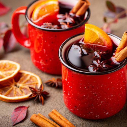 Xícara de quentão com canela e laranja, decorada com cravo, perfeita para festas juninas.