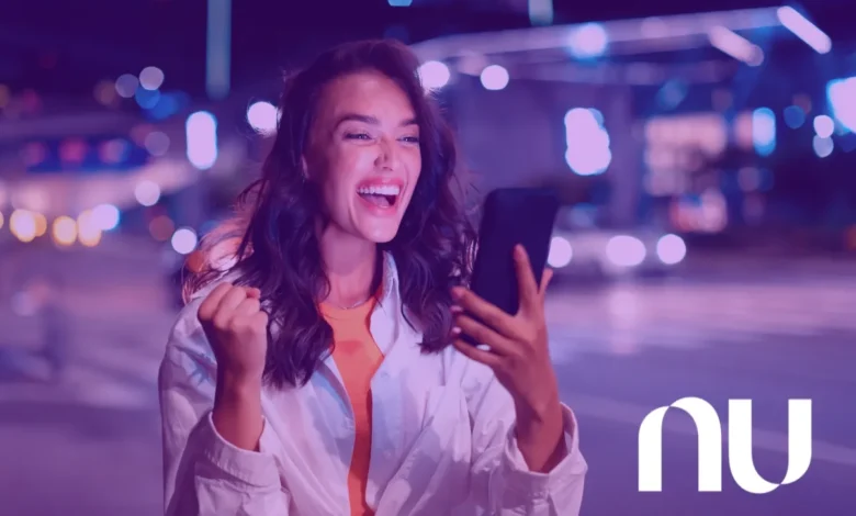 Mulher sorrindo ao usar o smartphone à noite, com luzes de cidade ao fundo, representando a inovação do Nubank.
