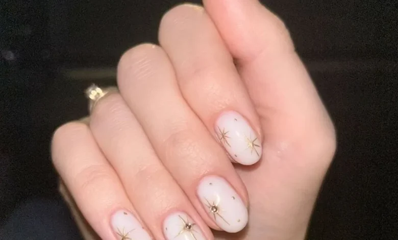 Unhas curtas e naturais com desenhos delicados e brilho dourado, estilo clean girl.