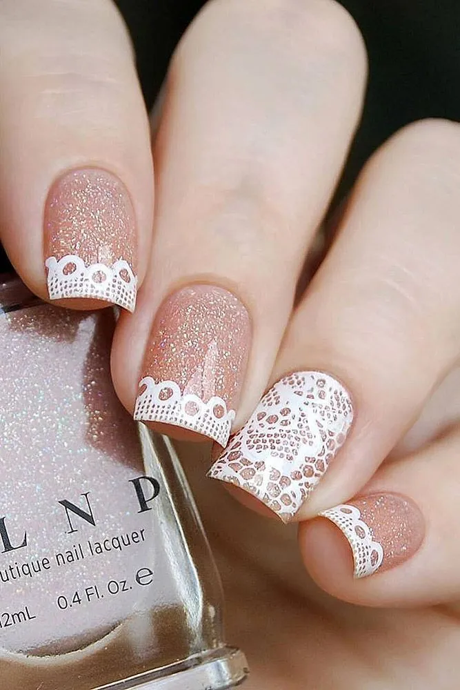 Unhas decoradas com renda, estilo romântico e delicado, com esmalte nude e detalhes brancos