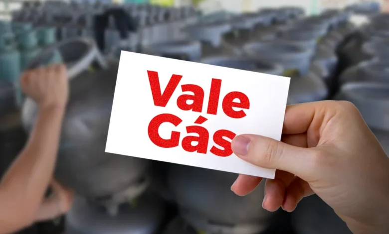Cartão do Vale Gás sendo segurado em meio a botijões de gás, representando o programa de auxílio social.