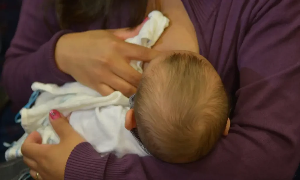 Mãe amamentando bebê nos braços, simbolizando cuidados no período de licença maternidade