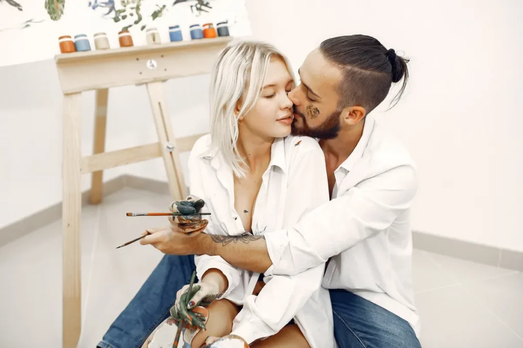Casal pintando e desenhando juntos em estúdio de arte, com mãos sujas de tinta