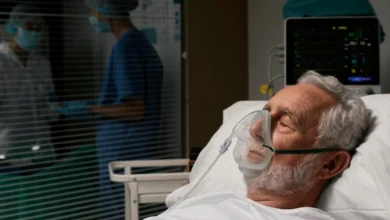 Paciente idoso em hospital recebendo oxigênio por máscara, representando o aumento dos casos de síndrome respiratória aguda grave no país.