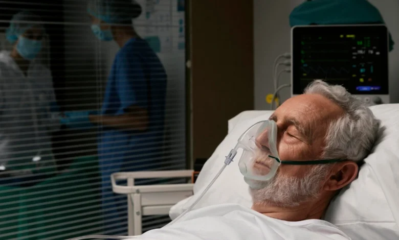 Paciente idoso em hospital recebendo oxigênio por máscara, representando o aumento dos casos de síndrome respiratória aguda grave no país.