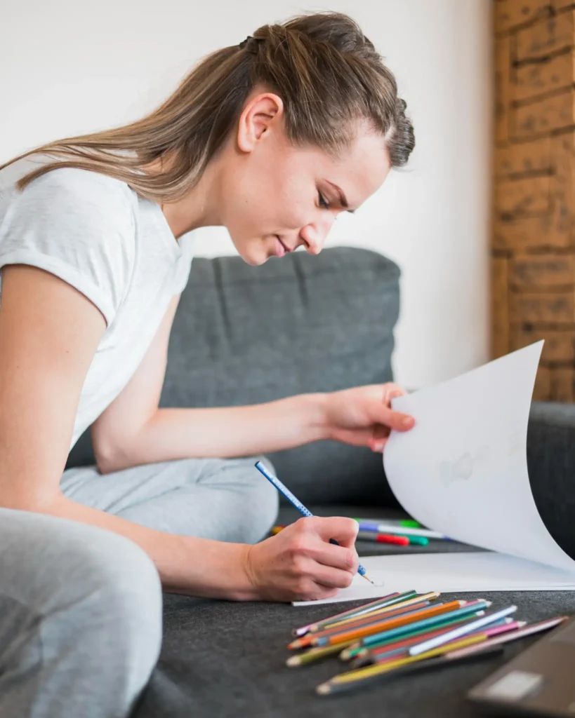 Mulher colorindo no sofá, destacando os benefícios terapêuticos e relaxantes da prática de colorir.