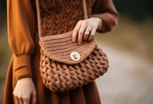 Bolsa de crochê marrom com alça, usada por mulher com vestido de tricô