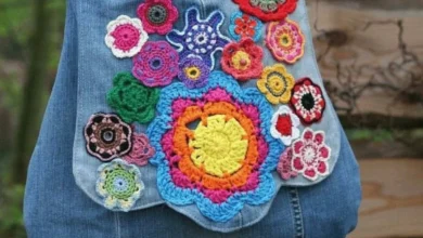 Bolsa jeans decorada com aplicações de flores de crochê coloridas.