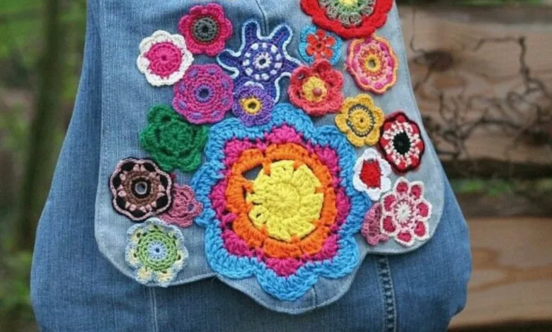 Bolsa jeans decorada com aplicações de flores de crochê coloridas.