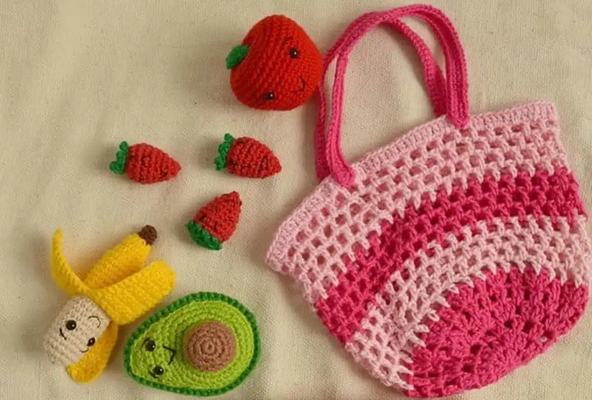 Bolsa de crochê e amigurumis de frutas, incluindo banana, morangos, abacate e melancia, em estilo colorido e divertido.