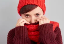 Mulher usando cachecol de crochê vermelho e marrom, protegendo-se do frio