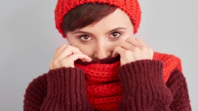 Mulher usando cachecol de crochê vermelho e marrom, protegendo-se do frio