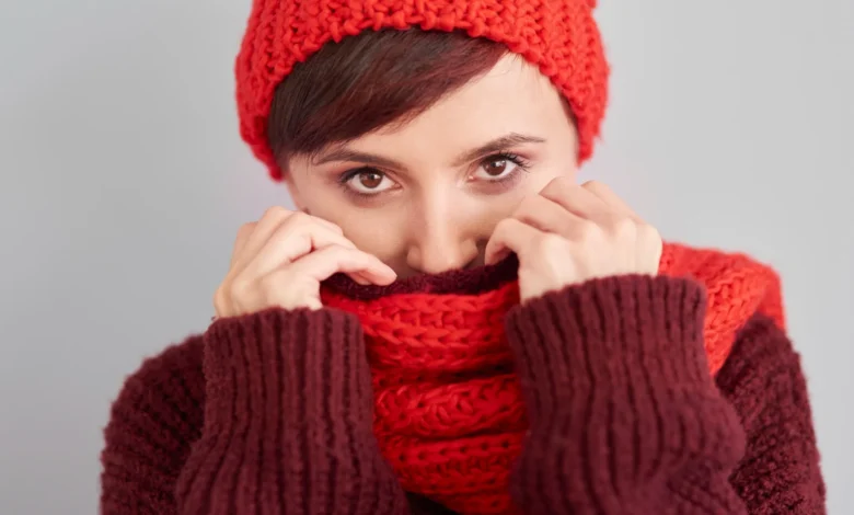 Mulher usando cachecol de crochê vermelho e marrom, protegendo-se do frio