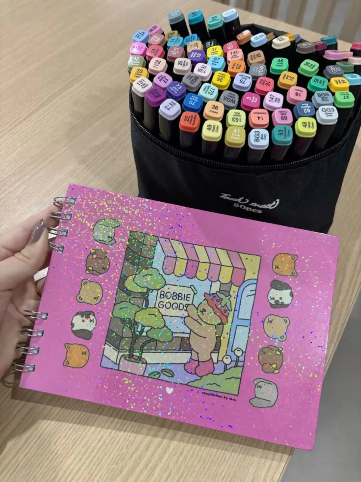 Canetinhas coloridas e caderno com capa de Bobbie Goods em estilo fofo