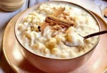 Canjica cremosa com leite condensado, polvilhada com canela, em uma tigela rústica.