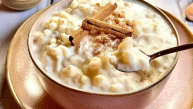 Canjica cremosa com leite condensado, polvilhada com canela, em uma tigela rústica.