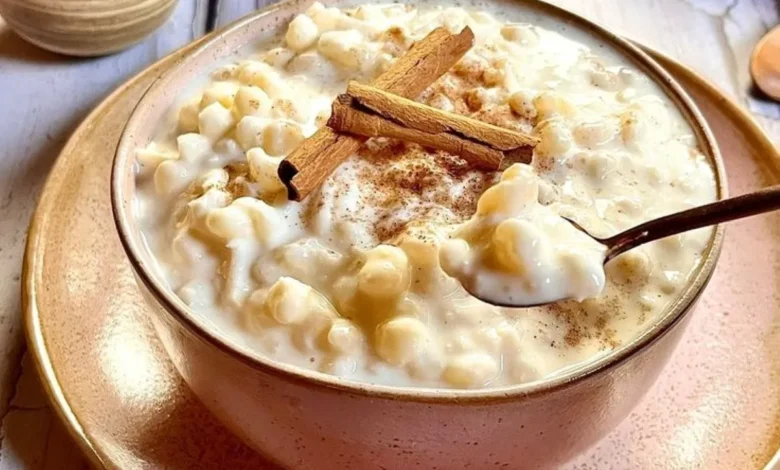 Canjica cremosa com leite condensado, polvilhada com canela, em uma tigela rústica.