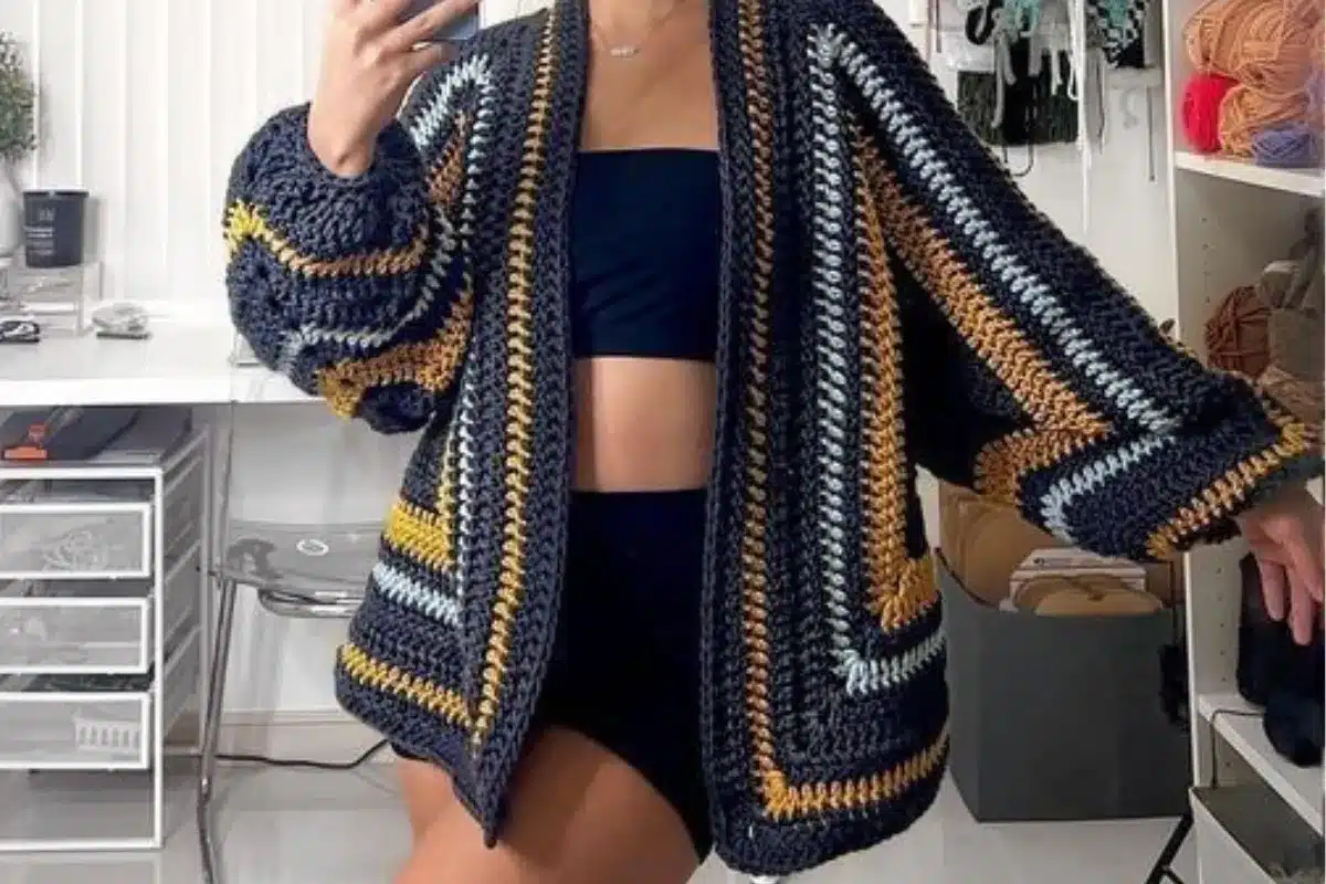 Cardigã de crochê listrado em tons escuros, azul e mostarda.